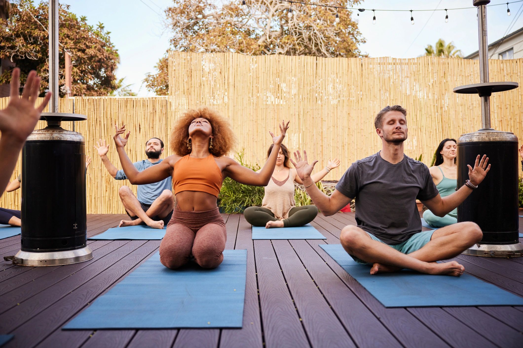 Diverse group meditating together outdoors during a wellness class