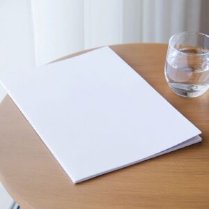 magazine mockup design. blank book mockup on wooden coffee table with glass of water